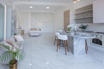 minimalistic light elegant luxury design of a modern spacious studio apartment with kitchen area, bedroom and huge mirror behind the couch. tiles on the floor and high ceiling.