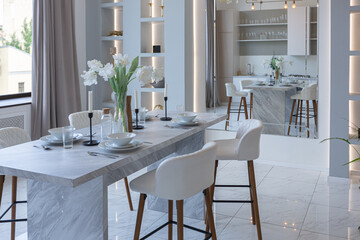 minimalistic light elegant luxury design of a modern spacious studio apartment with kitchen area, bedroom and huge mirror behind the couch. tiles on the floor and high ceiling.