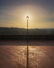 Lamp post on the Montescudaio terrace. Sun in the center and sea in the background. Tuscany