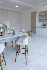 minimalistic light elegant luxury design of a modern spacious studio apartment with kitchen area, bedroom and huge mirror behind the couch. tiles on the floor and high ceiling.