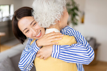 シニア女性を笑顔でハグをするミドル女性/家族