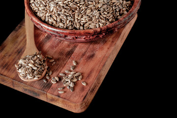 wooden spoon and bowl with seeds of milk thistle or Silybum marianum medicinal plant for liver isolated on black background