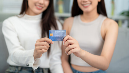 Close up hand of Two beautiful young women show their credit cards in the living room. The concept suggests inviting you to use credit cards to shop online.
