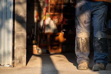 dirty trousers of worker in protective boots for occupational hazards in oil mill are shadows, unrecognisable person