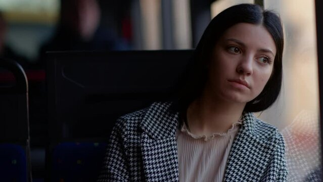 Pretty young brunette staring out the window while riding public transport. A young girl looks thoughtfully out the bus window