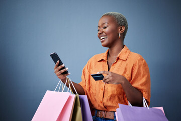 Bags, shopping and black woman with a credit card, cellphone and ecommerce on a grey studio...