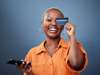 Portrait, phone and credit card with a black woman online shopping in studio on a gray background....