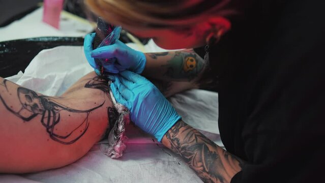 Tattooing process in a tattoo studio closeup of girls leg getting tattoo sketch. High quality 4k footage