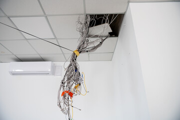 Electrical wires hanging from the ceiling. Cables hanging from ceiling of room. Building under construction.