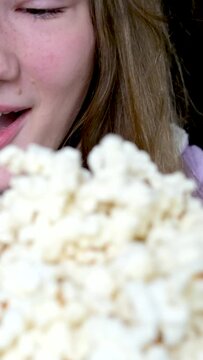 close-up slow motion video pouring a lot of popcorn scatters in different directions girl rejoices laughs looks at it, happy expression of a child of a young woman teenager smile sincere laughter