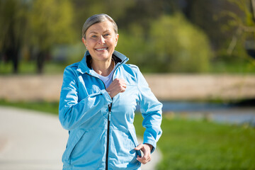 Mature good-looking woman running in the park and looking contented