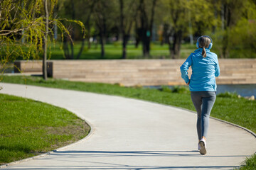 Woman in blue blazer listening to the music and jogging