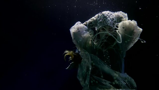 underwater fairytale and fantasy, slow motion diving woman in depth, mysterious undersea princess