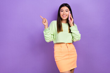 Fototapeta premium Photo of pretty shiny lady wear green sweatshirt speaking modern gadget showing empty space isolated purple color background