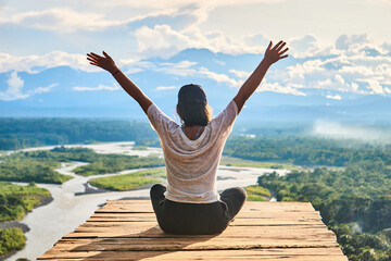 Unrecognizable woman enjoying freedom over wooden board on mountain