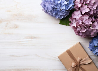 Top view image of hydrangeas with gift box on light wooden texture
