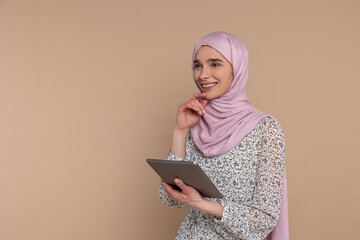 Young woman in hijab with a tablet looking involved