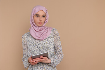 Pretty young muslim woman in hijab holding tablet in hands