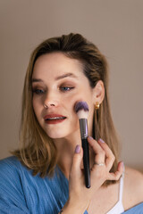 Fototapeta premium Young woman doing her make-up, with brush.