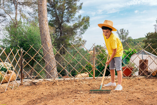 Kid in casual clothes preparing garden in countryside