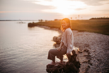 Young woman resting near lake, enjoying summer time.