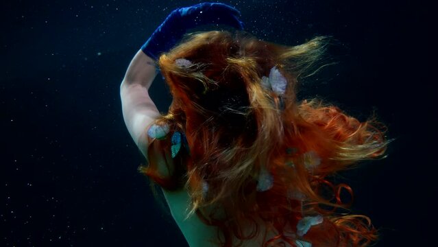 underwater mysterious shot with fabulous fairy with butterflies in hairstyle, back view of woman