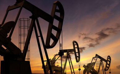 Oil pumps under a sunset sky. Fossil fuel issues and environmental concerns. - 619527557