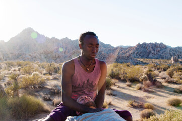 Fototapeta na wymiar Photographs of a young black gay man practicing Reiki in the desert. 