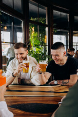 Happy group of friends drinking and clinking with beer and cocktails at brewery bar restaurant. Beverage life style concept with guys and girls having fun together