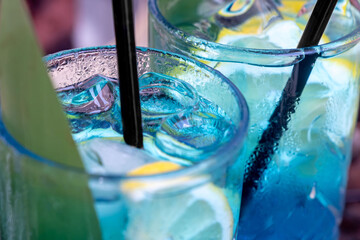 cold blue cocktails with ice and lemon in misted glasses close-up. Two soft drinks Blue Lagoon in...