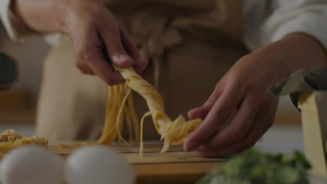 Cooking, chef baker Puts spaghetti pasta in nests in a pile In the home kitchen of a housewife. Pasta experts prepares pasta, cuts it carefully, uses modern methods of forming spaghetti, making pasta
