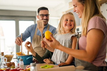 Happy family with children preparing healthy food together in kitchen