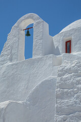Old Mediterranean Cycladean architecture white church with a small bell, under the sun in Mykonos, Greece.