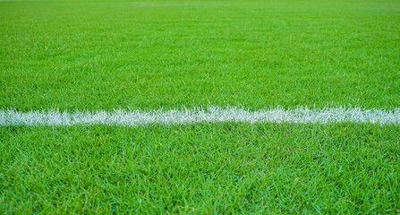 White lines on a horizontal green grass in a soccer field. Close-up of white stripes made in green grass at football stadium for background or texture © MrAnuwat