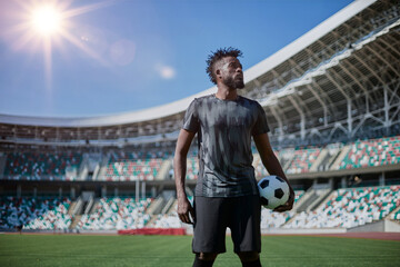 Intense portrait of a football player holding the ball in the stadium - Powered by Adobe