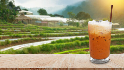 Iced thai milk tea in glass, Milk ice tea, Cheddar is a traditional Thai drink on wooden table with nature background, Summer drinks with iced