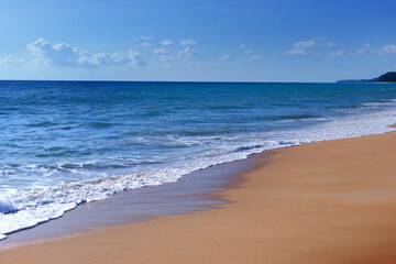 Fototapeta na wymiar Light blue sea waves and island on clean sandy beach, Tropical white sand beach and soft sunshine background