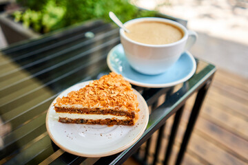 Cup of hot Peanut latte and Carrot pie. The table in the coworking space of the coffee shop. A cup of coffee on the veranda on a sunny day. Coffee break at the cafe. Close-up