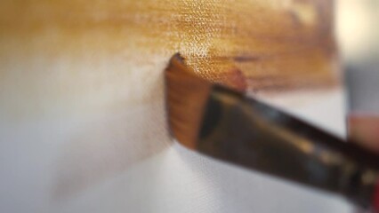 Female hand painting with brush acrylic or oil paint on canvas. Artist paints an oil painting in the studio, close-up, creator creates a work of art - Powered by Adobe