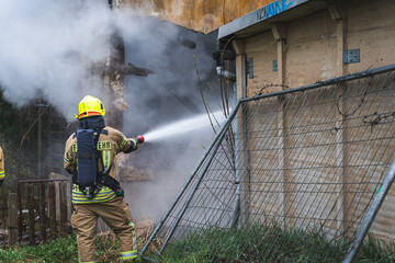 Ein Feuerwehrmann unter Atemschutz löscht einen Wohnhausbrand von außen...18.04.2023