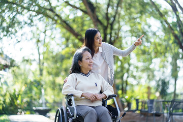 Asian senior woman in wheelchair with happy daughter. Family relationship retired woman sitting on wheelchair in the park age care at retirement home. © Charlie's