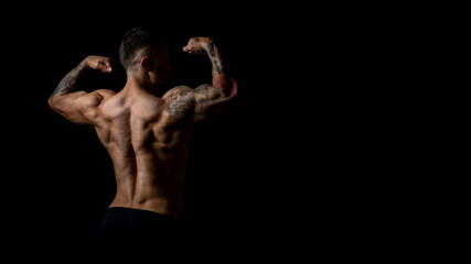 Obraz na płótnie Canvas Horizontal banner, back view of male bodybuilder with developed body muscles, studio photo on black background.
