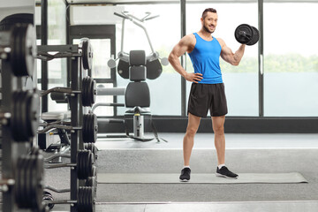 Obraz na płótnie Canvas Man exercising with a dumbbell at the gym