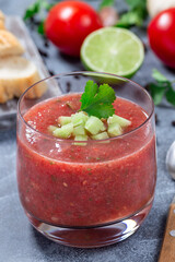 Gazpacho soup served in glass garnished with cucumber and cilantro, vertical