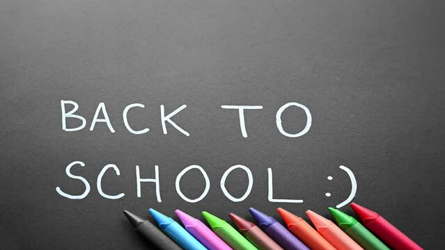 Back to school simple animation. Animation on black background. Stop motion animation. Handwritten text with white chalk on a blackboard. Colorful. Concept of education. Hand-drawn simple font.