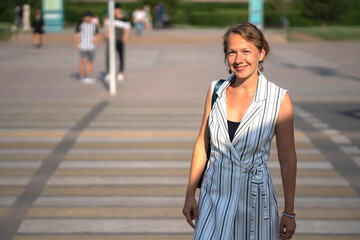 A young blonde woman crosses the road at a pedestrian crossing in the city center.