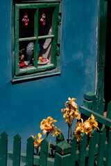 Architectural details of a blue old house with green windows. Spring flowers