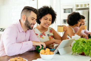 happy couple looking at tablet and touching screen at home