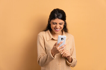 fun brazilian woman checking smartphone  in beige background. app, social media, addiction, network concept.