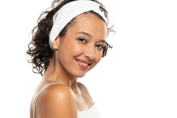 Young dark skinned smiling woman with makeup and headband posing on a white background